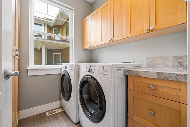 clothes washing area featuring cabinets, tile patterned floors, and washing machine and clothes dryer