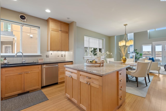 kitchen featuring sink, a center island, dishwasher, light stone countertops, and backsplash