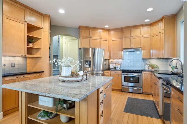 kitchen with light stone counters, sink, stainless steel appliances, and a center island