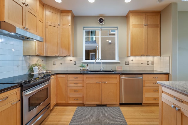 kitchen with appliances with stainless steel finishes, decorative light fixtures, sink, and light wood-type flooring