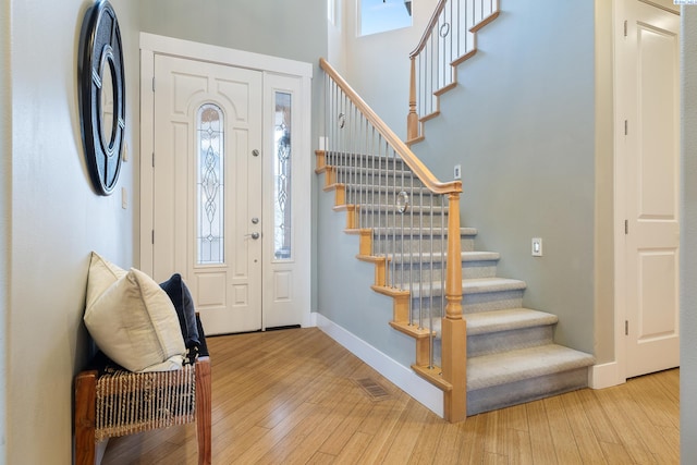 foyer featuring a towering ceiling and light wood-type flooring