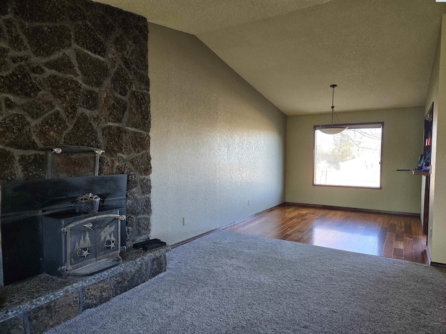 unfurnished living room featuring a textured wall, vaulted ceiling, a textured ceiling, and wood finished floors