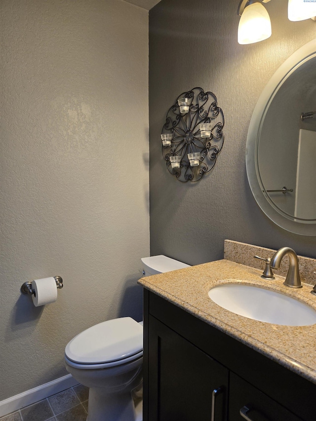 bathroom featuring baseboards, a textured wall, toilet, tile patterned floors, and vanity