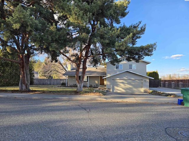 view of front of home with a garage, concrete driveway, and fence