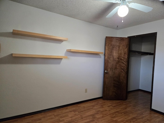 unfurnished bedroom with baseboards, ceiling fan, wood finished floors, a textured ceiling, and a closet