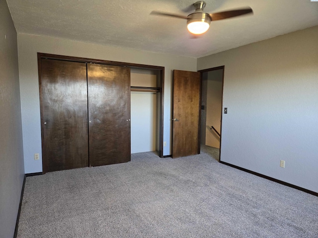 unfurnished bedroom featuring a closet, a ceiling fan, carpet flooring, a textured ceiling, and baseboards