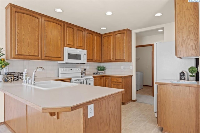 106 Muirfield Ln, Pasco, WA 99301 - kitchen featuring white appliances, a peninsula, light countertops, a breakfast bar, and decorative backsplash