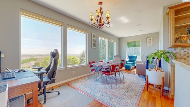 dining room with light wood-type flooring, a chandelier, and a wealth of natural light