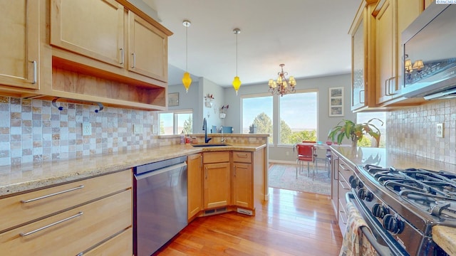 kitchen featuring a sink, a chandelier, stainless steel appliances, a peninsula, and light wood-type flooring