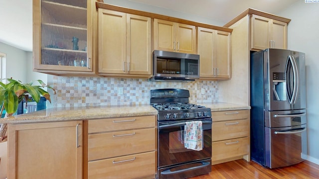 kitchen with backsplash, stainless steel appliances, light wood-style floors, and light brown cabinets