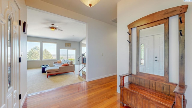 foyer entrance featuring a ceiling fan, baseboards, visible vents, and light wood finished floors