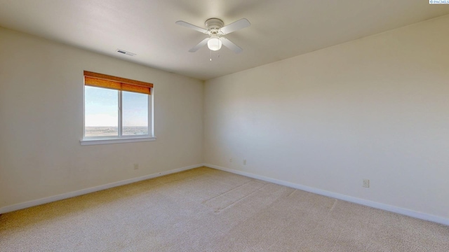 spare room with light colored carpet, a ceiling fan, baseboards, and visible vents