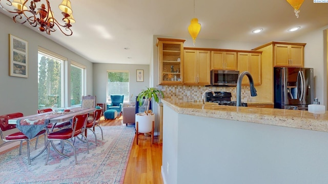 kitchen featuring decorative backsplash, recessed lighting, a chandelier, light wood-style flooring, and appliances with stainless steel finishes