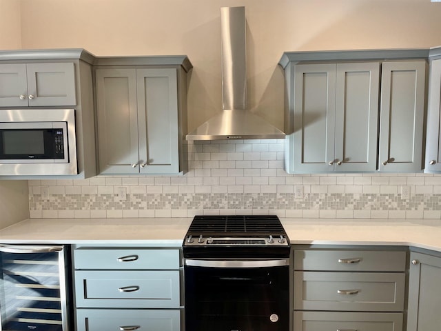 kitchen featuring stainless steel appliances, beverage cooler, gray cabinets, and wall chimney range hood