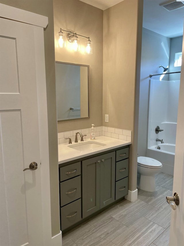 bathroom featuring visible vents, toilet, vanity, and bathtub / shower combination