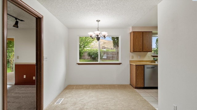 5456 Fern Loop, West Richland, WA 99352 - kitchen with dishwasher, a chandelier, a textured ceiling, brown cabinetry, and light carpet