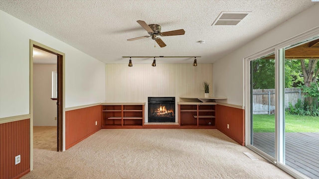 5456 Fern Loop, West Richland, WA 99352 - unfurnished living room with track lighting, light colored carpet, a glass covered fireplace, wainscoting, and ceiling fan