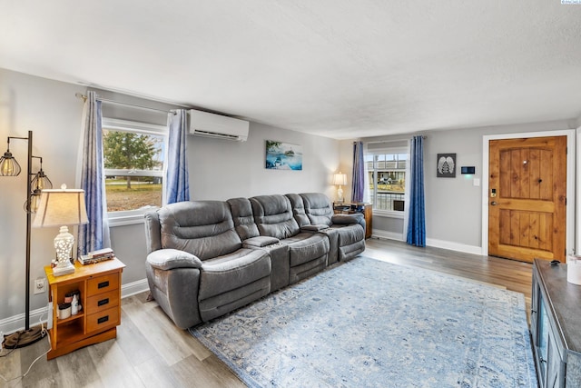 living room featuring a wealth of natural light, a wall unit AC, and light hardwood / wood-style floors