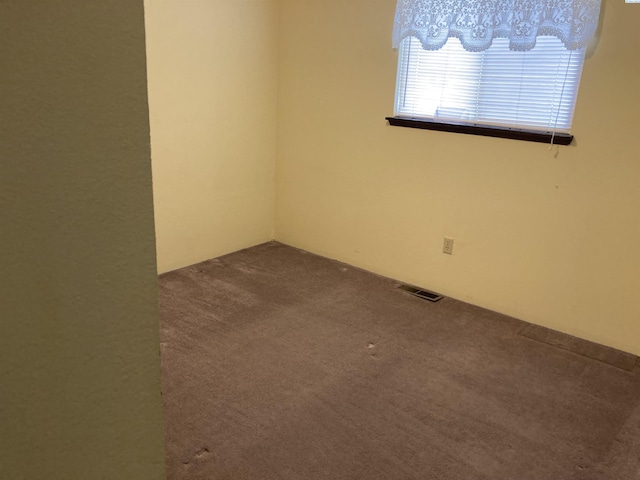 unfurnished room with visible vents and dark carpet