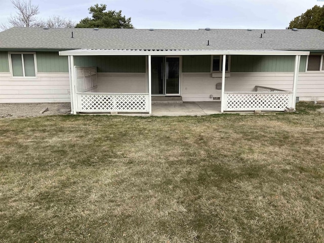 back of house featuring a yard, a shingled roof, and a patio area