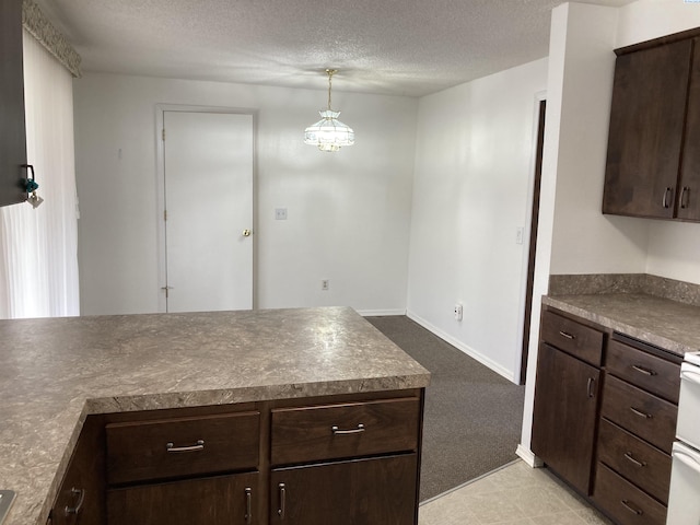 kitchen with dark brown cabinetry, baseboards, light colored carpet, decorative light fixtures, and a textured ceiling