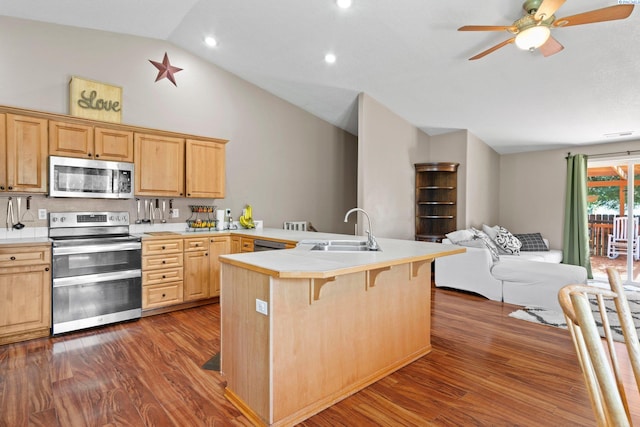 kitchen featuring sink, dark wood-type flooring, a breakfast bar area, and appliances with stainless steel finishes