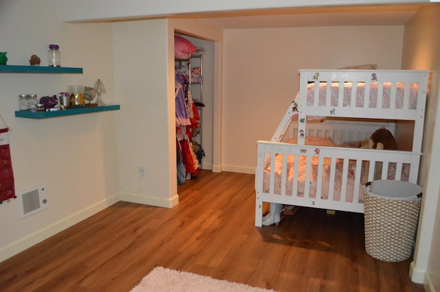 bedroom with a closet, wood-type flooring, and a nursery area