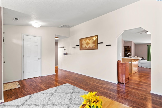 unfurnished room featuring sink, dark wood-type flooring, and a textured ceiling