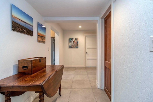 corridor with light tile patterned floors, recessed lighting, a textured wall, and baseboards