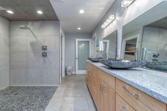 full bath featuring tile patterned floors, recessed lighting, a tile shower, and vanity