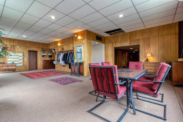 dining room with wooden walls, visible vents, and carpet floors
