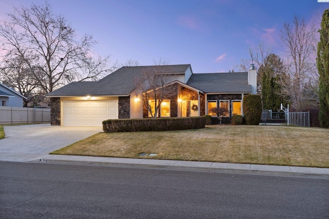 view of front of property with concrete driveway, stone siding, an attached garage, fence, and a front yard