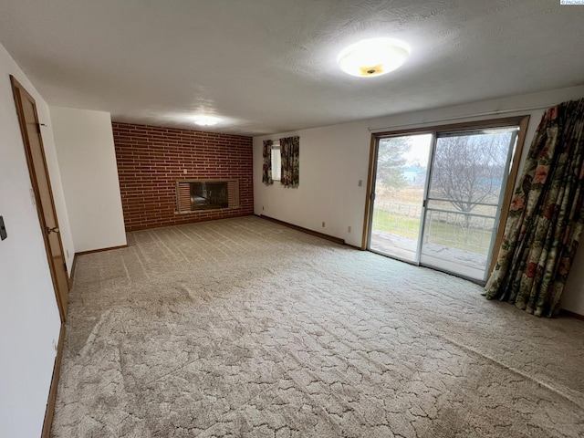 unfurnished living room featuring a textured ceiling, light carpet, brick wall, baseboards, and a brick fireplace