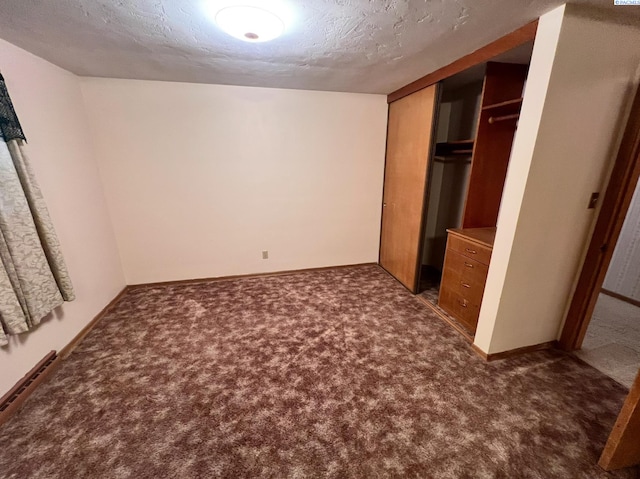 unfurnished bedroom with baseboards, a closet, dark carpet, and a textured ceiling