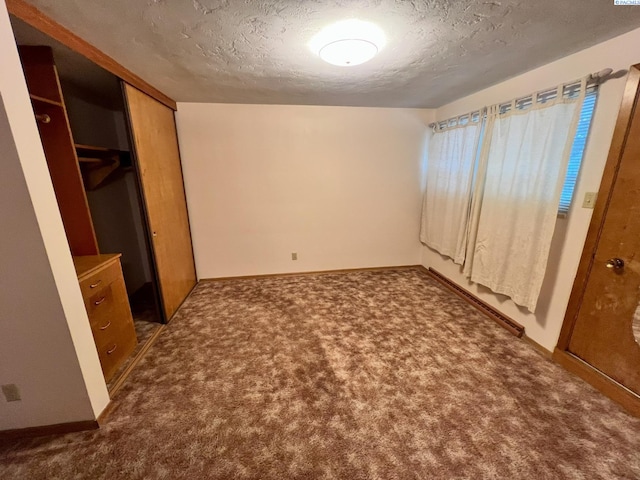 unfurnished bedroom featuring a closet, baseboards, dark colored carpet, and a textured ceiling