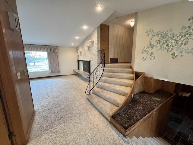 stairway featuring carpet floors, lofted ceiling, a brick fireplace, and recessed lighting