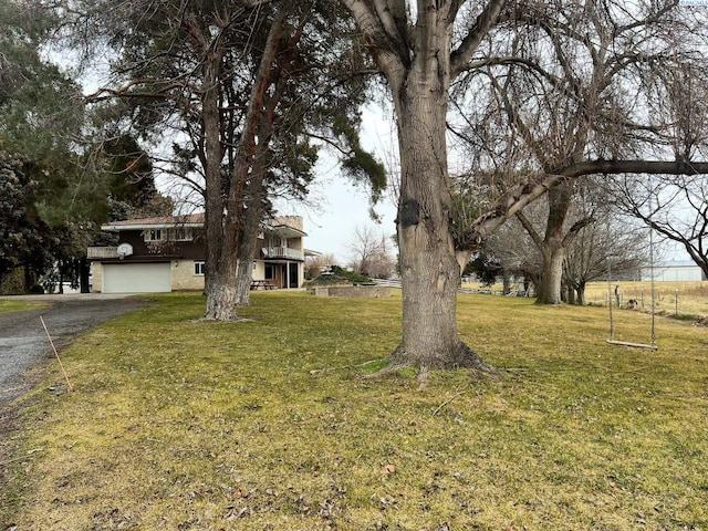 view of yard with a garage and aphalt driveway