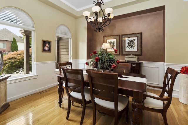 dining area featuring crown molding, a chandelier, and light wood-type flooring