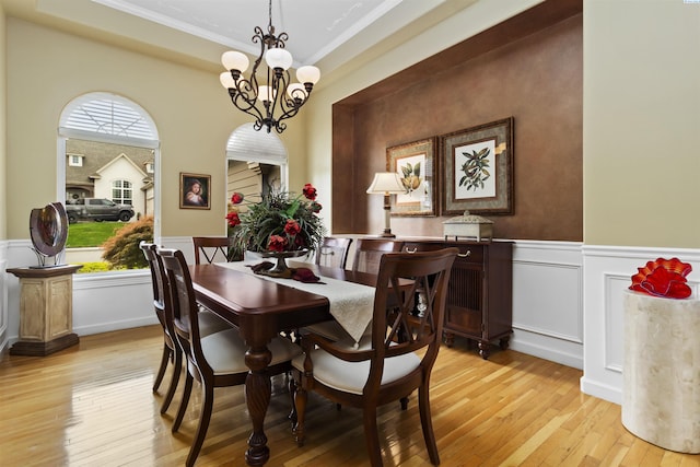 dining room with a notable chandelier, ornamental molding, and light wood-type flooring