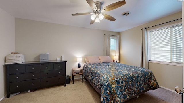 bedroom with baseboards, light carpet, a ceiling fan, and visible vents