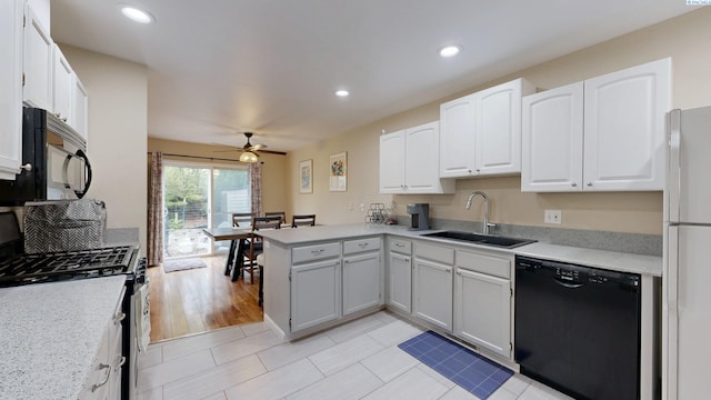 kitchen with a sink, white cabinets, a peninsula, and black appliances