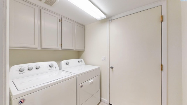 clothes washing area featuring separate washer and dryer, cabinet space, and visible vents