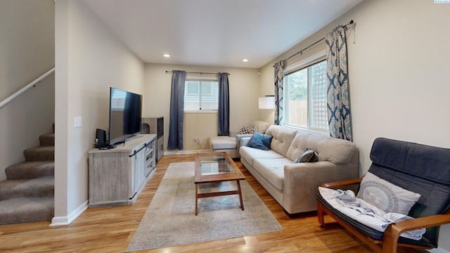 living room featuring light wood-type flooring, recessed lighting, stairs, and baseboards