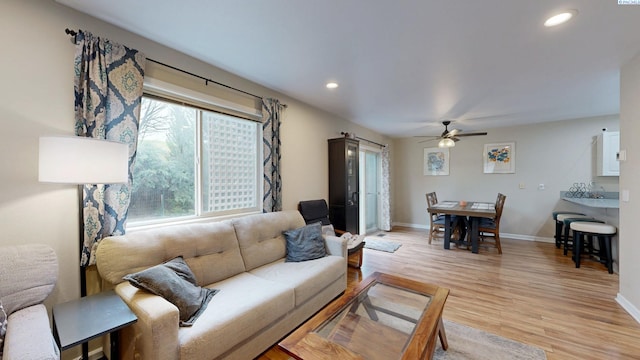 living room featuring light wood-style floors, baseboards, a ceiling fan, and recessed lighting