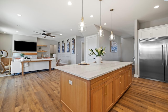 kitchen featuring pendant lighting, light hardwood / wood-style flooring, built in refrigerator, light stone counters, and a kitchen island