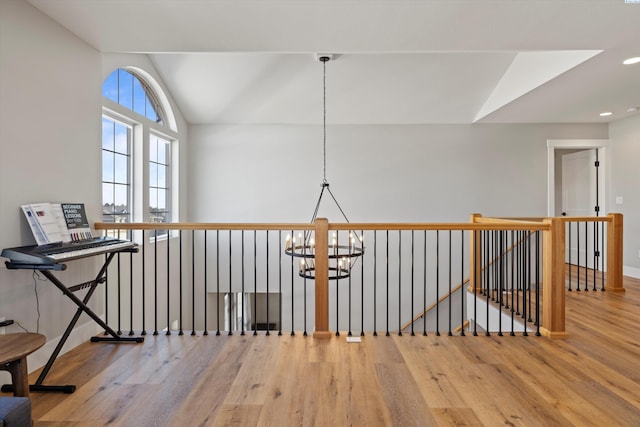 hall featuring lofted ceiling, a notable chandelier, and hardwood / wood-style flooring