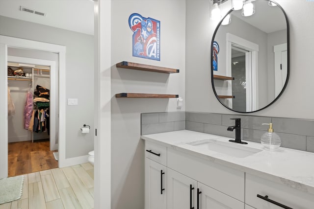 bathroom with vanity, backsplash, hardwood / wood-style flooring, and toilet