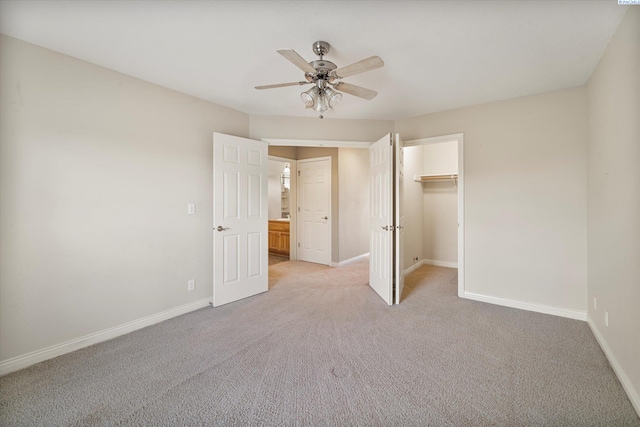 unfurnished bedroom featuring light colored carpet, baseboards, ceiling fan, a closet, and a spacious closet