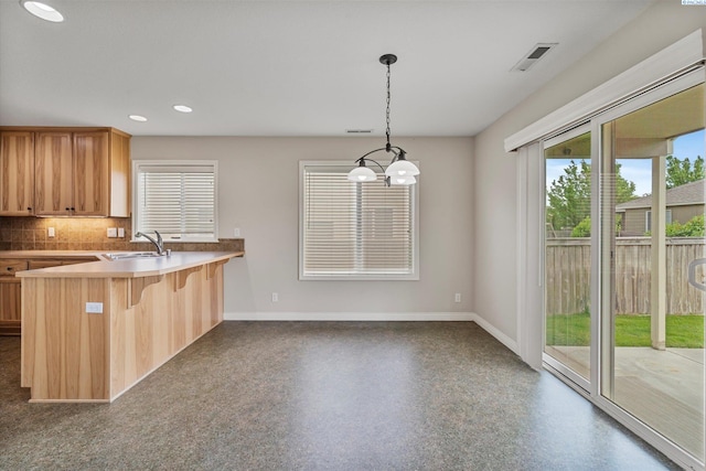 kitchen featuring a sink, healthy amount of natural light, baseboards, a breakfast bar area, and recessed lighting