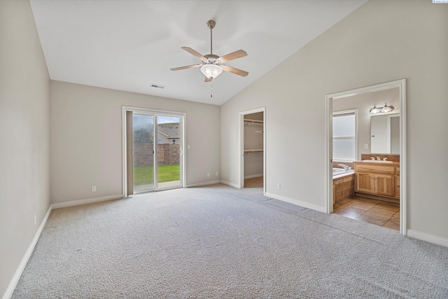 unfurnished bedroom with light colored carpet, lofted ceiling, baseboards, a spacious closet, and access to outside